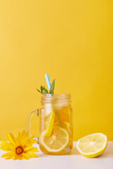 Glass of lemonade with lemon and mint, drinking straw in glass cup isolated over yellow background,...