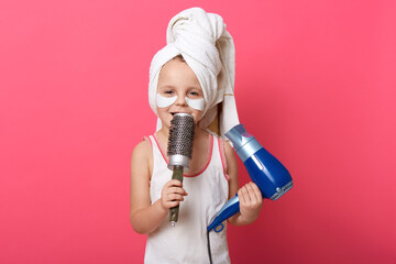 Cute female child imagines she super star and singing with comb in hands ,charming little girl with...
