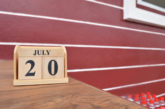 July 20, Number cube with wooden table beside the wall.
