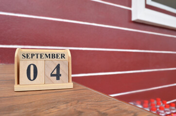 September 4, Number cube with wooden table beside the wall.