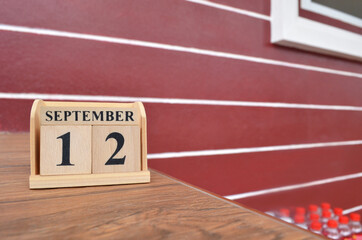 September 12, Number cube with wooden table beside the wall.