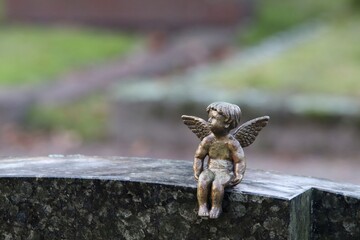 A decorative small metal angel figure on top of a gravestone. Concepts of death, faith, after life...