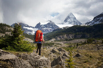 Naklejka premium Adventure Backpacking in the Iconic Mt Assiniboine Provincial Park near Banff, Alberta, Canada. Girl Hiker with Canadian Mountain Landscape in Background.