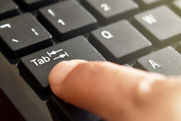 Finger pressing enter Tab button on keyboard.