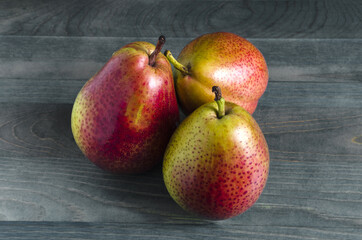 three ripe pears on a wooden background close up