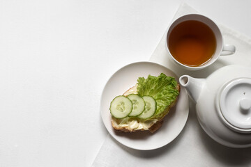 Breakfast in a white bowl on a light background croissant with herbs, vegetables, butter, cheese, herbal, green tea, flower, fruit, yogurt