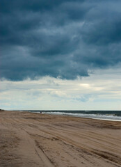 Fototapeta na wymiar Couple walking along the ocean shore against a dramatic sky.