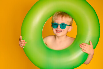 Happy cute baby boy 6-7 years old in sunglasses and with a life buoy. Summer and the sea.