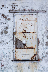 Old door in the wall. Weathered rough rusty surface of a closed door.