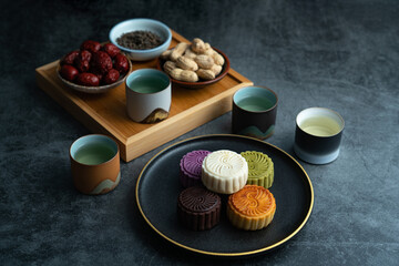 Colorful moon cakes are placed on black plates. Chinese traditional food mid autumn moon cake