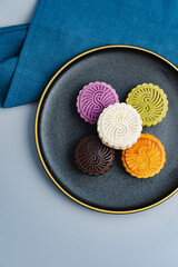 Colorful moon cakes are placed on black plates. Chinese traditional food mid autumn moon cake