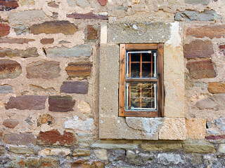 Old window with creative metal bars on the white stone wall