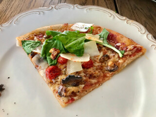 Homemade Pizza Slice with Parmesen Cheese Slice, Arugula, Rucola or Rocket Leaves in Plate.