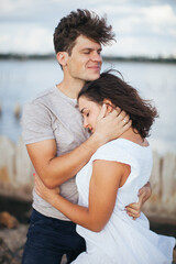 Obraz premium Beautiful people in love. The woman put her head on the man's shoulder.A married couple is relaxing at the sea. A woman in a white dress on the beach. Husband and wife walking along the beach. Love. R