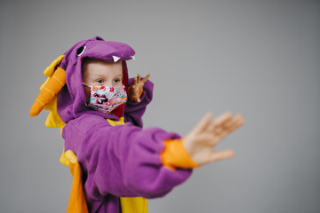 beautiful young girl with nose and mouth mask dressed in dragon costume during corona crisis