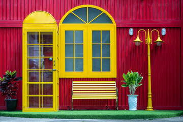 Yellow telephone box, bench and lamppost on the background of a red metal wall on the street of Danang city in Vietnam