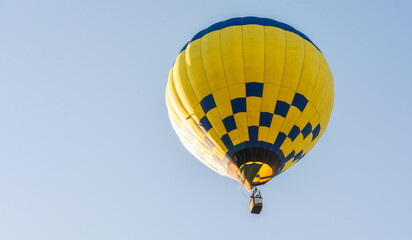 Fototapeta premium Balloon flying high in the sky. Balloon basket with people. Aeronautic sport. Burning gas. Bright multi-colored balloon. Romantic trip. Free space for text.