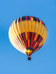 Balloon flying high in the sky. Balloon basket with people. Aeronautic sport. Burning gas. Bright multi-colored balloon. Romantic trip. Free space for text.