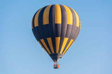 Fototapeta premium Balloon flying high in the sky. Balloon basket with people. Aeronautic sport. Burning gas. Bright multi-colored balloon. Romantic trip. Free space for text.