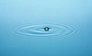 close up of drop and ripples on a water surface.