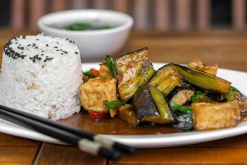 Lightly fried tofu and stew with eggplant, onion, garlic, gravy sauce on plate