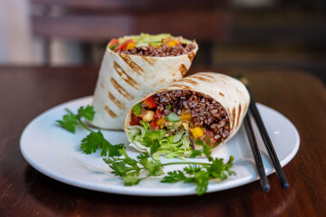 Vegan burrito. Sliced up raw food wrap with vegan ingredients on a plate
