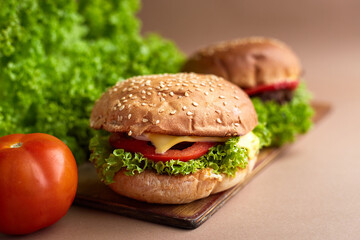 Closeup of a fresh homemade beef burger with tomato, cheese, onion and salad. Street food, fast food.