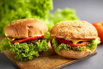 Closeup of a fresh homemade beef burger with tomato, cheese, onion and salad. Street food, fast food.