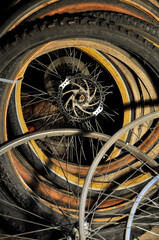Fototapeta na wymiar Old rusty bicycle wheels and tires in messy composition in dark room / space. 