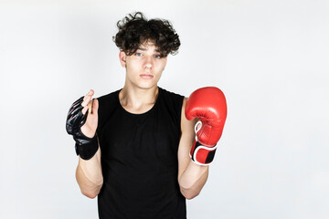 A teenage sportsman chooses which sport is more effective, on one hand he has a boxing glove and on the other hand there is a mixed martial arts glove