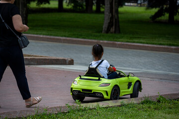 little boy riding a green electric car