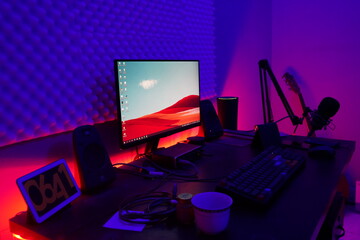 A desktop computer setup with colorful lights behind desk
