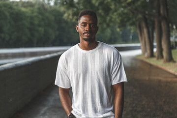 Young man smiling at camera in a park. Horizontally framed shot.