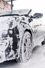 Gray car on the side in the foam from the detergent stands at the sink