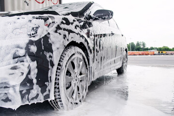 Gray car on the side in the foam from the detergent stands at the sink