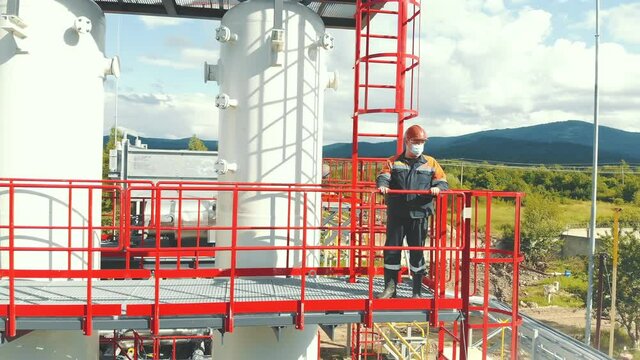 Aerial view gas station operator climbs to the top of the station. Modern gas complex in the mountains. A gas worker climbs the ladder of the gas distribution unit against the backdrop of mountainous