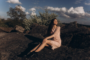 Young brunette girl portrait outdoors in grey mountains outdoors. Woman beauty concept