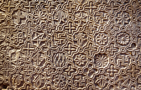 Byzantine patterned ornament carved in stone wall, ancient texture background, detail of interior with geometric relief.