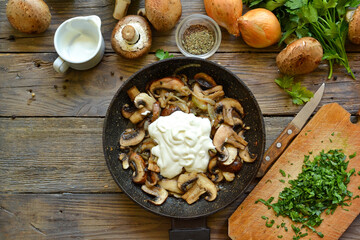 Royal champignons in sour cream sauce. Recipe. Step by step cooking mushrooms with onions. Wood background. Top view. Food in the pan. Fried mushrooms and sour creame
