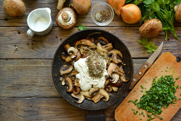 Royal champignons in sour cream sauce. Recipe. Step by step cooking mushrooms with onions. Wood background. Top view. Food in the pan. Fried mushrooms, sour cream and spices