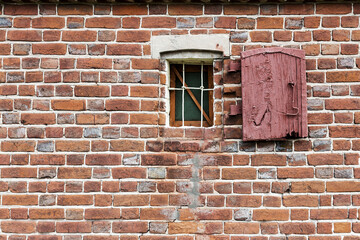 Old window with creative metal bars on the white stone wall