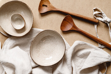 Modern minimalist ceramics set with a linen cloth over kraft paper background. Natural products or food concept, top view, flat lay.