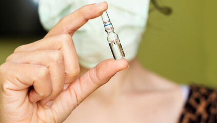 closeup woman wear mask and holding Medical ampoules vial