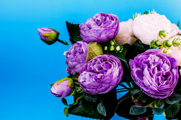 artificial  purple and white peonies on a blue background