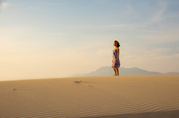 Fototapeta na wymiar Girl walks on windy sand desert. Fridom and relax concept