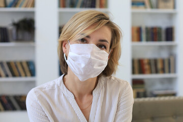 Middle aged woman in medical mask at home during epidemic situation.