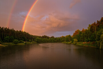 Beautiful evening sunset landscape with lake and rainbow, spring and forest in Vereshchytsia, Lviv district. june 2020.