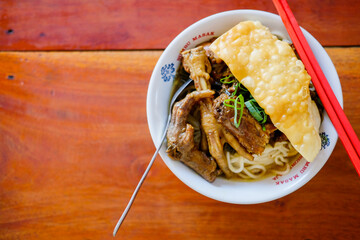 Mie Ayam or chicken noodle, with chicken feet, Indonesian cuisine. Served with fried wonton, and scallion.