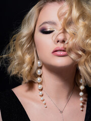 Gorgeous blonde, portrait on a black background. Beautiful young girl, makeup for the celebration.