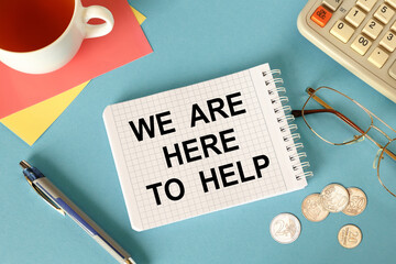 We are here to help is written on a notepad, on an office desk with office accessories.